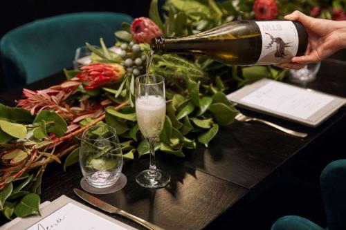 a person pouring a glass of champagne on a table at The Victoria Hotel in Melbourne