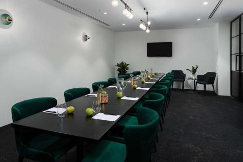 a conference room with a long table and green chairs at The Victoria Hotel in Melbourne