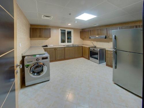 a kitchen with a washing machine and a refrigerator at Aryana Hotel in Sharjah