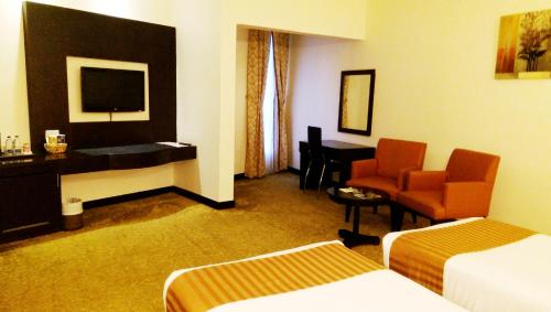 a hotel room with two beds and a desk and a chair at Aryana Hotel in Sharjah