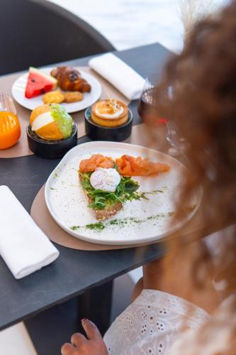 a woman sitting at a table with a plate of food at Bolina Suite & Spa in Milano Marittima