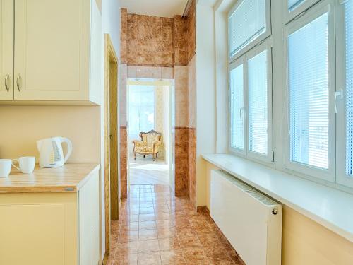 a kitchen with white cabinets and a hallway with windows at Lyra Apartments in Karlovy Vary