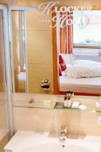 a bathroom with a sink and a mirror and a bed at Hotel Klockerhof in Lermoos