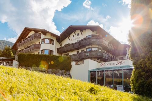 a building on a hill with the sun in the sky at Hotel Klockerhof in Lermoos