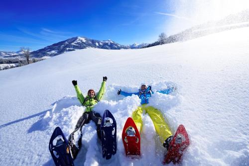 two people laying in the snow in the snow at Seeblick 7 in Zell am See