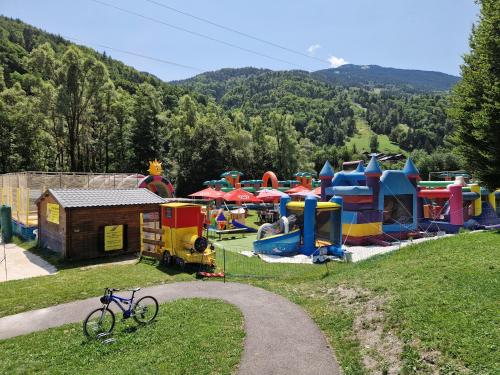 un vélo garé dans un parc avec une aire de jeux dans l'établissement Summer Alps Apartment, à Saint-Martin-de-Belleville
