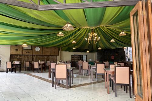 a dining room with a green ceiling and tables and chairs at Hotel Pesona Bamboe Lembang in Genteng