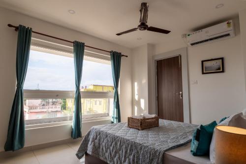 a bedroom with a bed and a large window at Borail Homes in Silchar