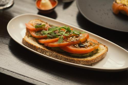 a sandwich with tomatoes on a plate on a table at Torel Saboaria in Porto