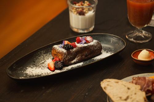 a piece of cake with berries on a black plate on a table at Torel Saboaria in Porto