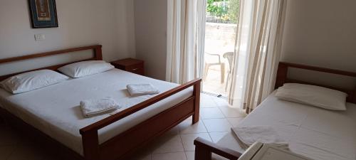 a bedroom with two beds and a large window at El Doro Rooms in Dhërmi