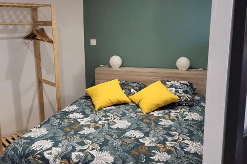 - une chambre avec un lit et 2 oreillers jaunes dans l'établissement Logement saisonnier la bourboule, à La Bourboule