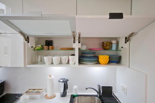 - une cuisine avec des placards blancs, de la vaisselle et un évier dans l'établissement Apartament SUNNY Przy Rynku z klimatyzacją i parkingiem, à Kielce