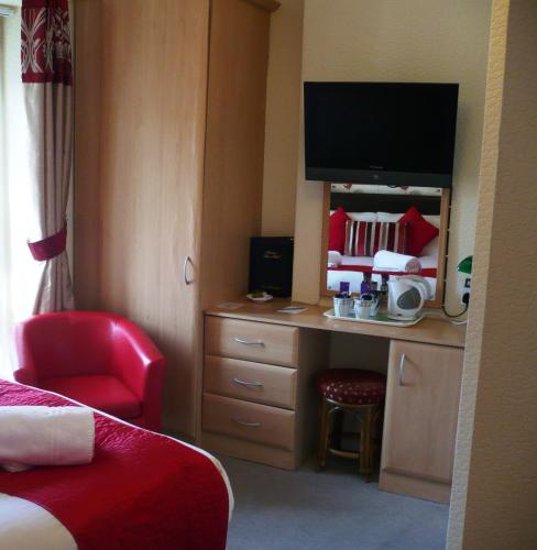 a hotel room with a desk with a tv on it at Milverton House in Llandudno