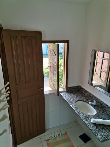 a bathroom with a sink and a mirror and a door at Hospedaria Cosanostra in Itaúnas