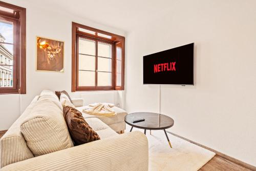 a living room with a couch and a tv on a wall at A&Y LakeHouse Golden Swan in Luzern
