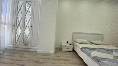 a white bedroom with a bed and a window at Уютная 1-ком кв в Жк Альтаир мкр Батыс-2 in Aktobe