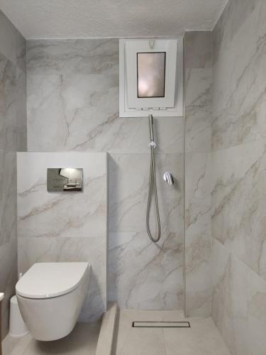 a white bathroom with a toilet and a shower at Seafront Apartment Pefkochori in Pefkochori