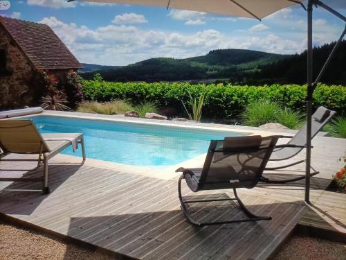 a deck with two chairs and an umbrella next to a pool at Au cœur des prés in Montmort