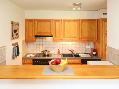a kitchen with wooden cabinets and a bowl of fruit on a counter at Apartment Cascades d'Eden 2 by Interhome in Crans-Montana