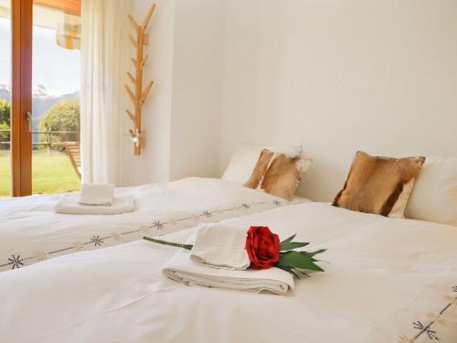 two beds with white sheets and a red rose on them at Apartment Cascades d'Eden 2 by Interhome in Crans-Montana