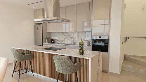 a kitchen with a counter with two chairs and a stove at STAY Oasis Luxury Villas in Ayia Napa