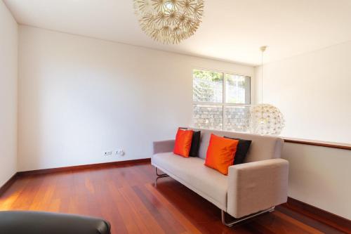 a living room with a couch with two orange pillows at GuestReady - Spacious stay with sea views in Caniço
