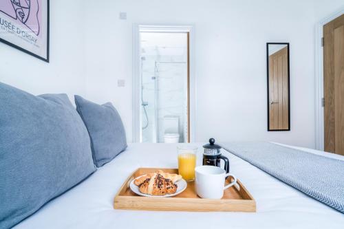 a tray with a plate of food and drinks on a bed at Cozy 2 Bedroom Apartment in Sutton in Sutton