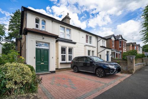 a black car parked in front of a white house at Cozy 2 Bedroom Apartment in Sutton in Sutton