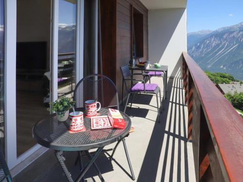 a table on a balcony with mugs on it at Apartment Europa Ouest - APT 74 by Interhome in Crans-Montana