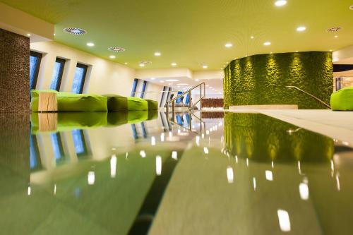 a empty room with a table and green chairs at Aqua Dome 4 Sterne Superior Hotel & Tirol Therme Längenfeld in Längenfeld