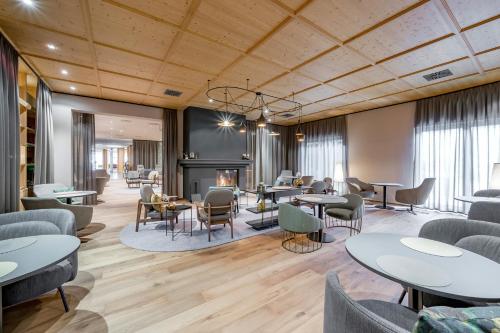 a lobby with tables and chairs and a fireplace at Aqua Dome 4 Sterne Superior Hotel & Tirol Therme Längenfeld in Längenfeld