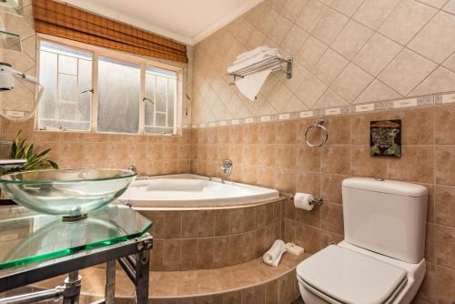 a bathroom with a tub and a toilet and a sink at Ipe Tombe Guest Lodge - Midrand in Midrand