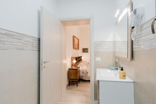 a white bathroom with a sink and a bedroom at Casa Vacanza Nonna Rosina in Castelvetrano Selinunte