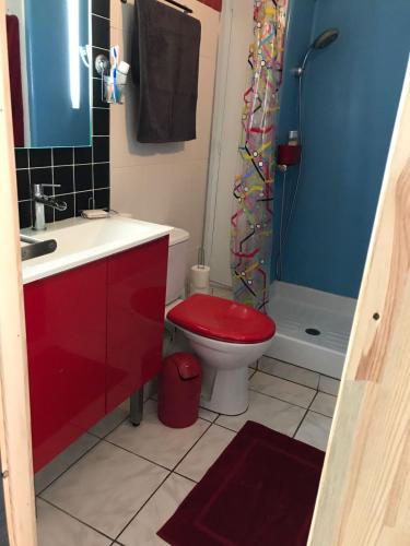 La salle de bains est pourvue d'une douche et de toilettes rouges. dans l'établissement T2 Les pieds dans l'eau vue Front de mer, à Saint-Cyprien