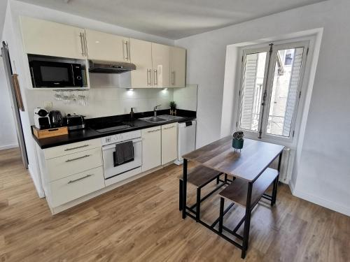 a kitchen with white cabinets and a wooden table at L'éclat urbain in Chambéry