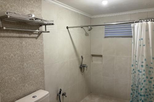 a bathroom with a shower curtain and a toilet at Hotel Pesona Bamboe Lembang in Genteng