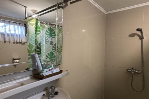 a bathroom with a shower and a sink and a mirror at Hotel Pesona Bamboe Lembang in Genteng