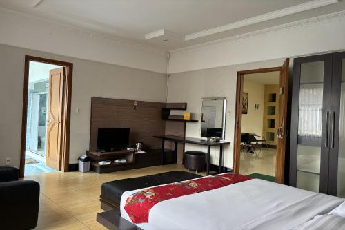 a bedroom with a bed and a desk and a television at Hotel Pesona Bamboe Lembang in Genteng