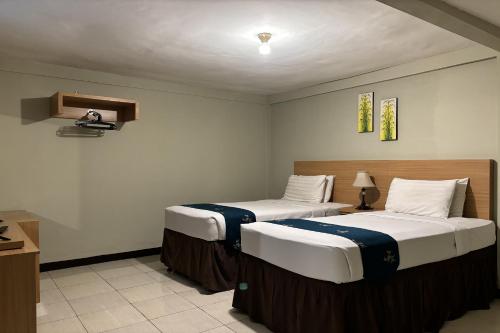 a hotel room with two beds in a room at Hotel Pesona Bamboe Lembang in Genteng