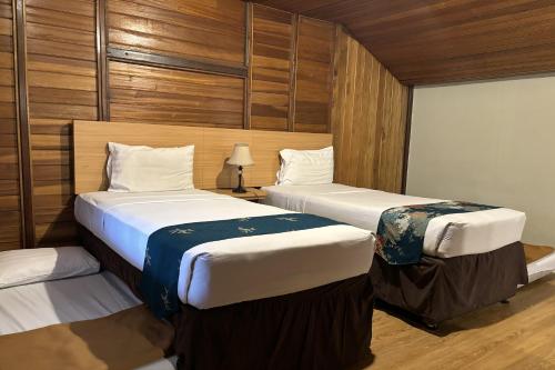two beds in a room with wooden walls at Hotel Pesona Bamboe Lembang in Genteng