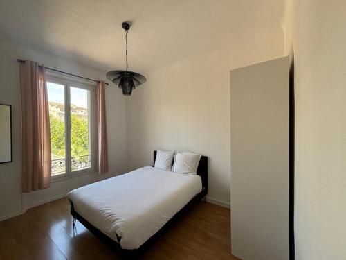 une chambre avec un lit blanc et une fenêtre dans l'établissement Appartement de charme proche stade Vélodrome, à Marseille