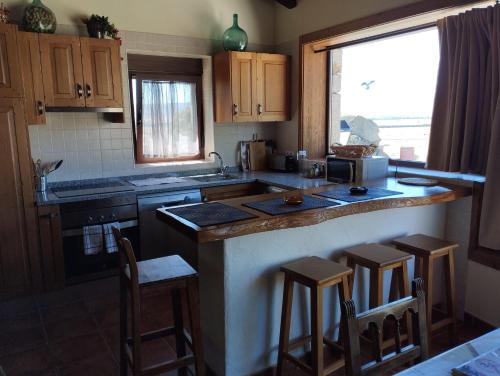 a kitchen with a counter and some bar stools at Entre las Piedras y musgo in Muñopepe