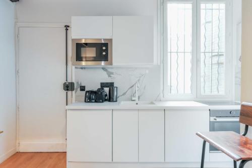 une cuisine blanche avec un évier et un micro-ondes dans l'établissement Relaxing Urban Getaway, Notre Dame, à Paris