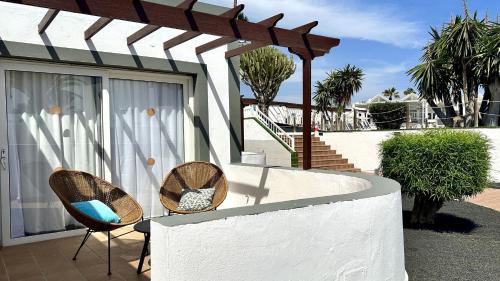 two chairs sitting next to a white wall at Caleta Dorada in Caleta De Fuste