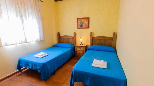 two beds in a room with blue sheets at La Chumbera Órgiva by Ruralidays in Órgiva