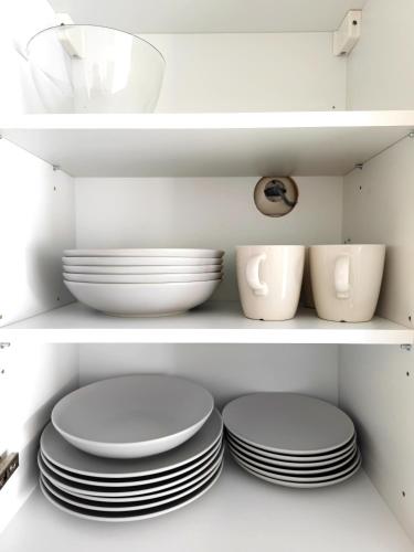 a shelf with plates and bowls in a kitchen cabinet at Wohlfühlen im Studio nahe Messe und Airport in Leinfelden-Echterdingen