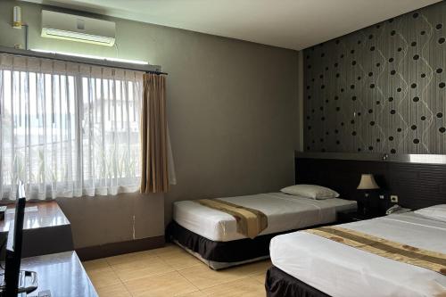 a hotel room with two beds and a window at Hotel Pesona Bamboe Lembang in Genteng