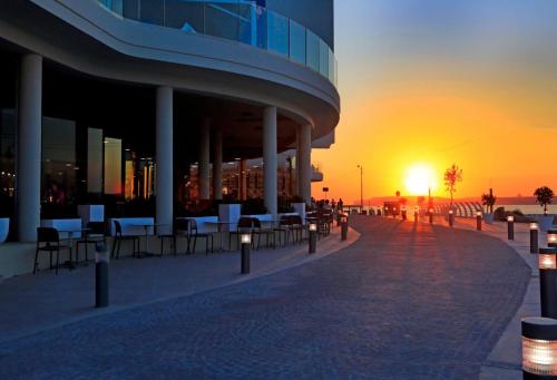 a building with tables and chairs in front of a sunset at Riviera Spa Resort - Adults Only in Mellieħa