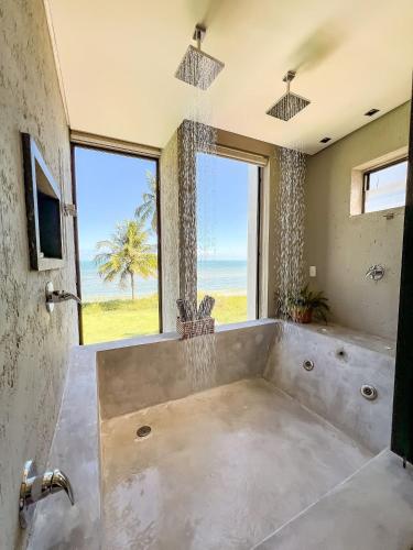 a bathroom with a large tub with a view of the ocean at Casa Waua | PÉ NA AREIA, rooftop, borda infinita in Barra do Camaragibe